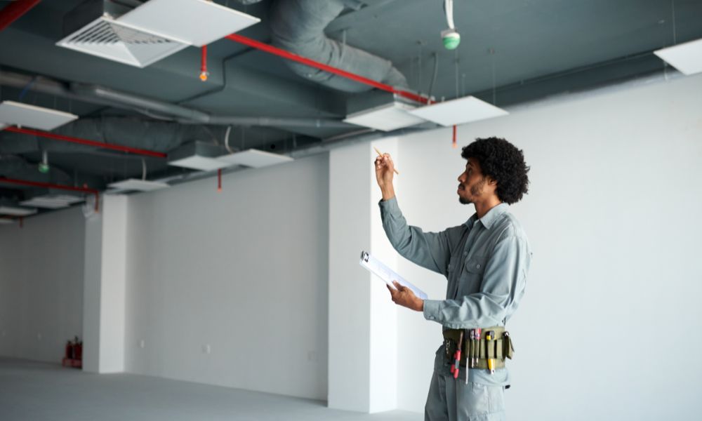 HVAC Inspection for Elevation Compliance in Flood Zones - ALTA Survey Alabama A building inspector evaluating ceiling-mounted HVAC systems in a commercial property, ensuring elevation compliance in a flood-prone area.