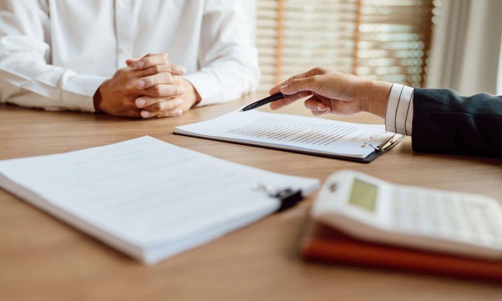 Reviewing FEMA Elevation Certificate and Construction Compliance Documents - ALTA Survey Alabama Two professionals reviewing FEMA Elevation Certificate documents for flood zone compliance and long-term insurance viability