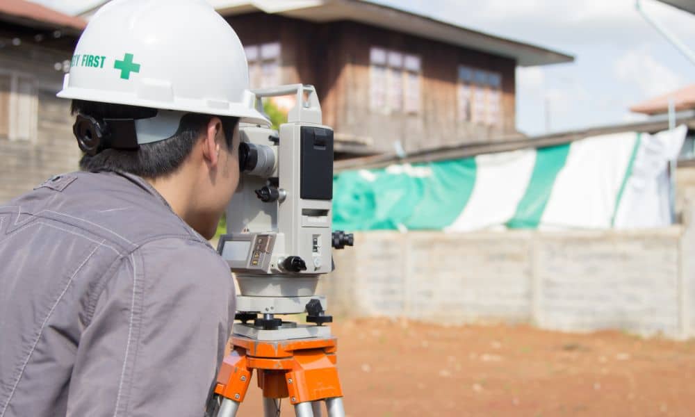  Land surveyor performing a boundary survey on a residential property using a total station instrument.
