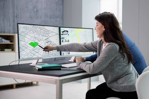 Professional reviewing a plat map on screen during a boundary survey to identify property lines and legal descriptions.