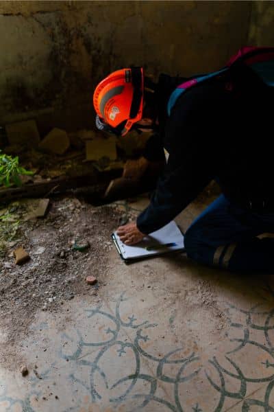 Surveyor inspecting soil and documenting storm damage as part of a boundary survey after heavy rains

