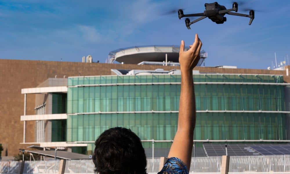 A licensed pilot launches a drone near a modern city building for drone mapping work under new municipal rules