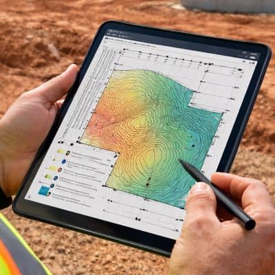Construction site topographic review - ALTA Survey Alabama Engineer reviewing drone surveying data on a tablet with topographic map at an active construction site