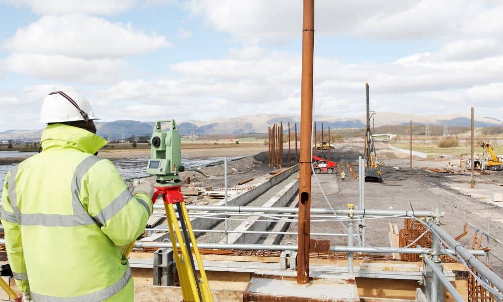 Surveyor taking precise field measurements on an active construction job site