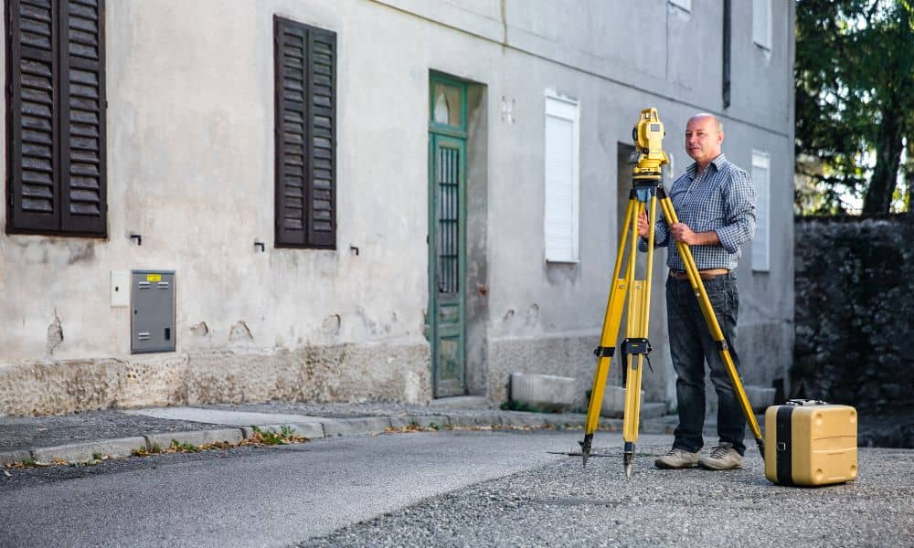 Surveyor measuring building elevation - ALTA Survey Alabama Land surveyor measuring a property for a flood elevation certificate