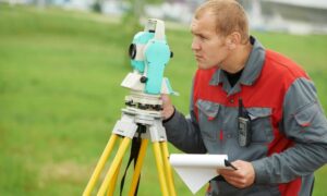 A licensed land surveyor measuring property boundaries using a total station during a field survey