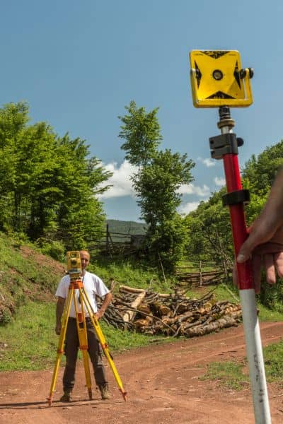Land surveyor measuring ground elevation for an elevation certificate using surveying equipment