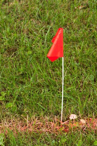 Property line marker flag placed in grass by a residential surveyor to show boundary before building