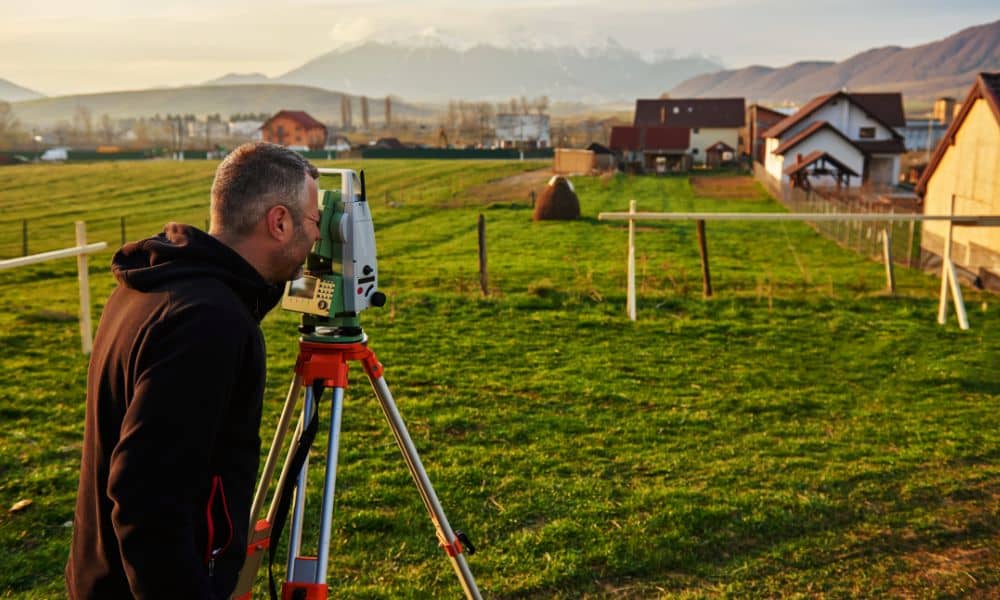 Residential surveyor checking property lines on open land before building a fence or shed