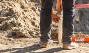 Worker placing a stake and string line during a construction survey to check the layout on site