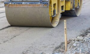 Survey stake marking site layout near construction equipment showing potential issues identified during an ALTA survey