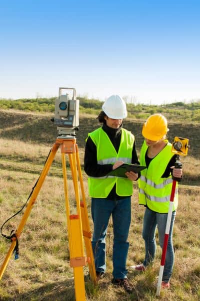 Land surveyors using equipment in the field to perform a boundary survey and mark accurate property lines