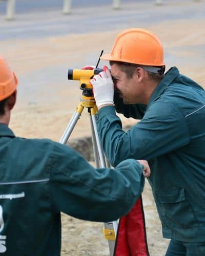 Surveyor using a level instrument to check measurements during a construction survey