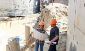 Two professionals reviewing site plans at a commercial construction property during the planning process