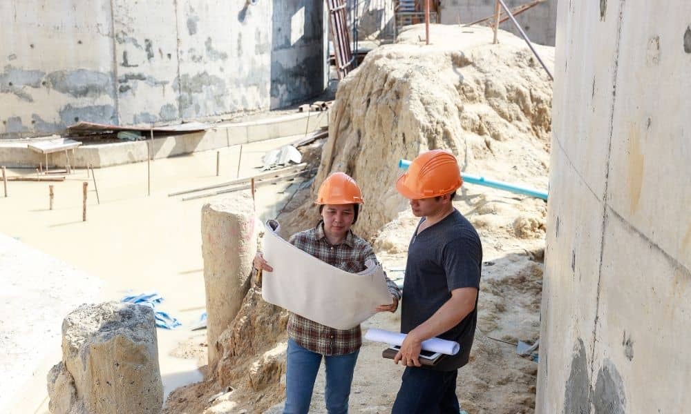 Two professionals reviewing site plans at a commercial construction property during the planning process