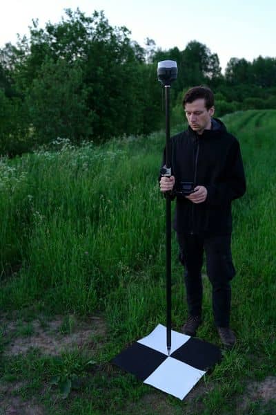 Surveyor using GPS equipment beside a ground control point for drone surveying and aerial mapping